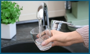 Water glass being filled at a faucet
